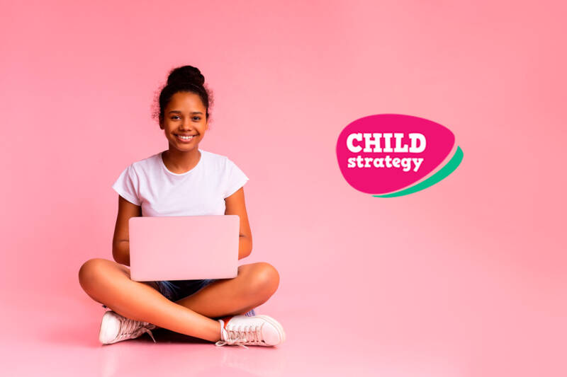 An ethnic, happy girl is sitting on the floor with a computer.