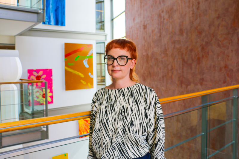 Woman with glasses standing in front of paintings